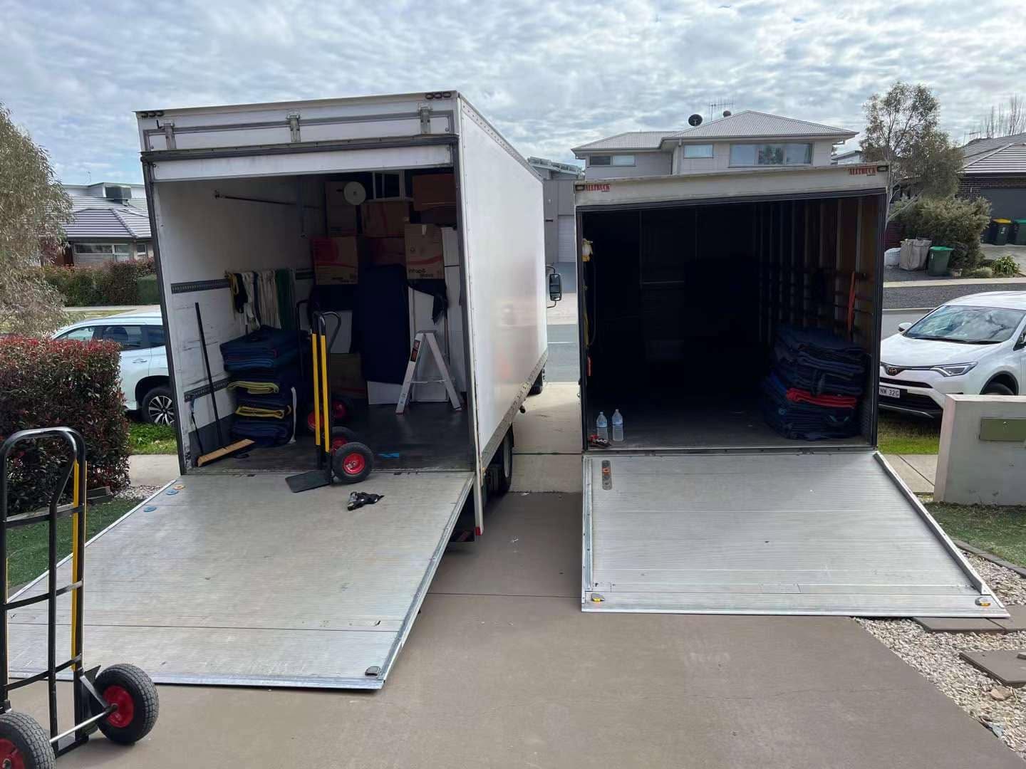 Two Truckmen trucks with ramps down loading into storage